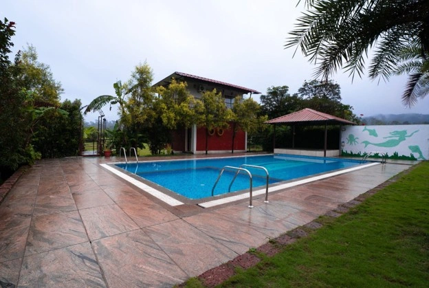 Luxury swimming pool at Streamedge Sakleshpur surrounded by lush
                            greenery