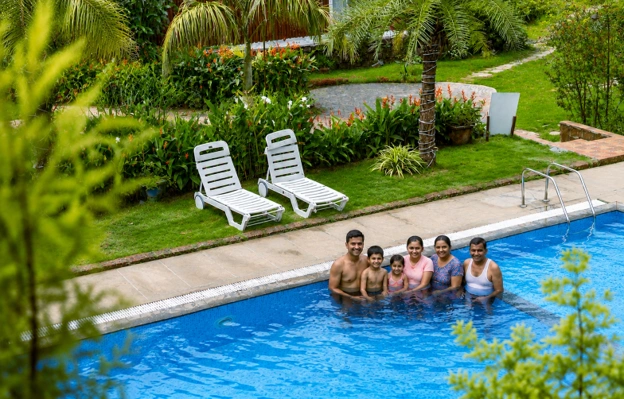 Family enjoying a swimming pool at Streamedge Sakleshpur surrounded by
                                nature